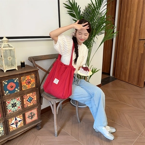 Lifestyle shot of large red drawstring striped tote bag with white logo on casual canvas