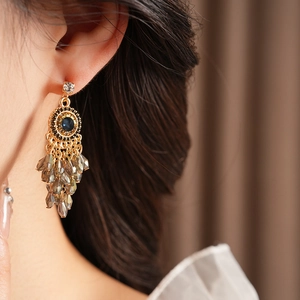 Close-up of bohemian tassel earrings with blue stones and crystals on a model