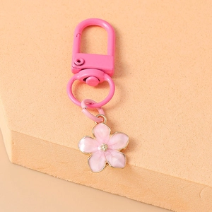 Detailed view of pink enamel cherry blossom keychain with gold-plated metal flower charm