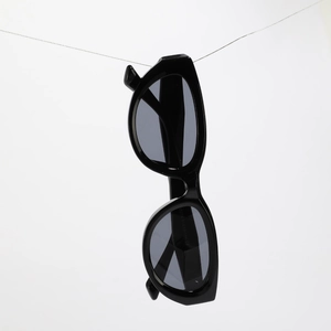 Square cat-eye black sunglasses with rivet detail hanging in modern minimalist display