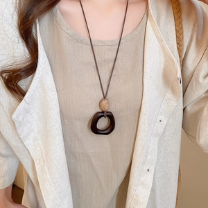 Detail of a vintage resin and wood pendant necklace on a linen garment