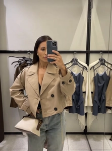Detail of khaki double-breasted short trench coat showing lapel and mirror selfie styling