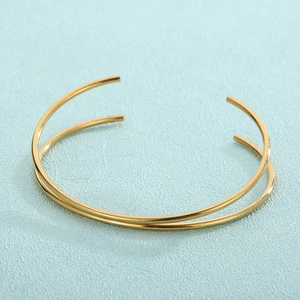 Detail of minimalist gold-plated titanium steel open bangle with parallel thin round bands