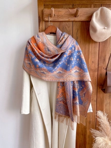 Ethnic blue and orange printed shawl scarf with fringe on a white coat and vintage door