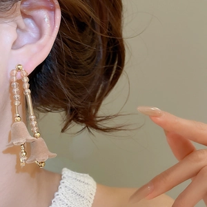 Primo piano dei pendenti a forma di mughetto con cristalli champagne e lunghe nappe