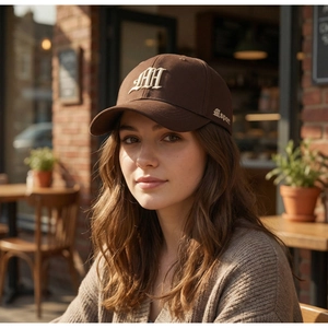 Detail of dark brown baseball cap with white HH embroidery in a cozy outdoor setting