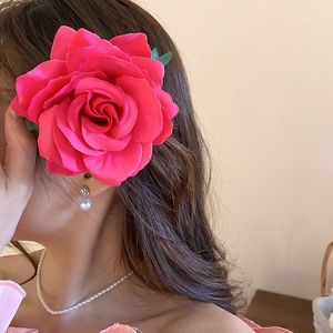 Close-up of a large magenta fabric rose hair clip worn on long wavy hair with elegance