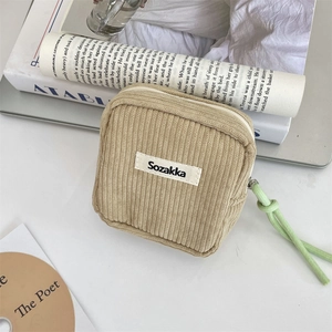 Detailed texture of khaki corduroy makeup bag with a green zipper pull on vintage books