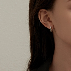 Detail of twisted silver hoop earring with colorful zircon inlay worn by a model