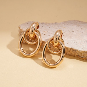 Interlocking gold geometric hoop earrings displayed on a natural stone background
