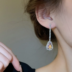 Detail of silver long fringe earrings with iridescent teardrop rhinestones on a model
