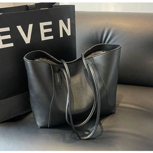 Detail of a minimalist black tote bag on a leather sofa with refined leather texture