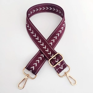 Detail of burgundy woven strap with silver chevron pattern and gold metal lobster clasps
