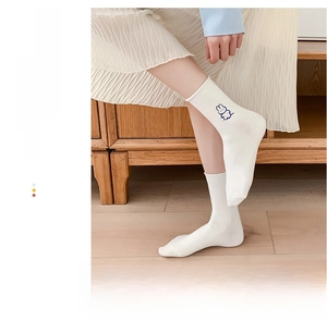 Close-up of white cotton mid-tube socks with cute rabbit embroidery and ribbed texture