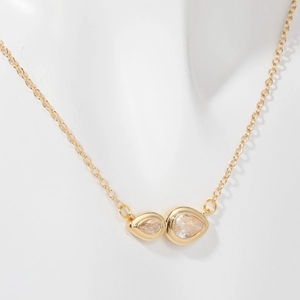 Detail of gold pendant necklace with water drop zircons displayed on a white mannequin