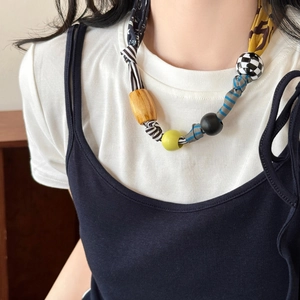 Detailed close-up of handmade beaded necklace with wooden beads and fabric elements