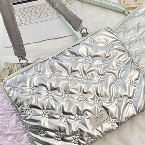 Detail of silver quilted laptop bag with 3D bow texture and stylish fabric brand tag