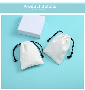 Flat lay of small white cotton drawstring jewelry bags with black cords and a gift box