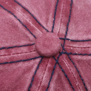 Macro detail of dark pink washed denim baseball cap crown with blue contrast stitching