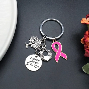 Detailed keychain with Tree of Life, winged heart, and pink ribbon on black surface