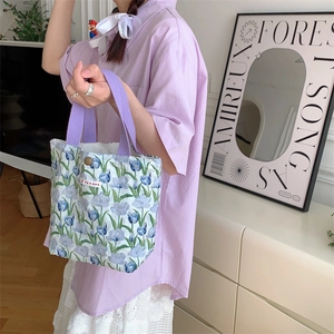 Dettaglio della borsa da pranzo in tela floreale con tulipani blu e manici viola