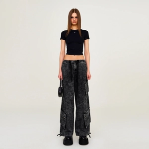 Vorderansicht eines schwarzen Crop-Tees mit grauer Acid-Wash-Cargohose und kleiner Tasche