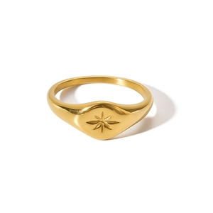 Macro detail of gold-plated signet ring with vintage engraved starburst on flat oval surface