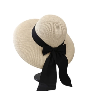 Elegant wide brim straw sun hat with a large black bow for summer beach vacations