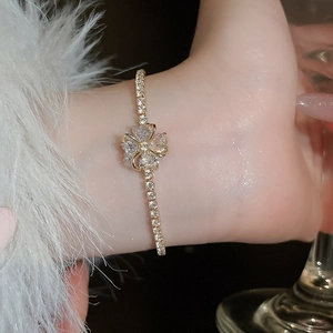 Detail of elegant gold clover bracelet with zircon crystals on a female wrist