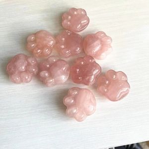 Polished pink rose quartz cat paw stone carvings displayed on a natural wooden surface