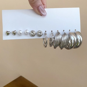 Detailed view of a six-pair silver earring set featuring heart studs and chunky hoops
