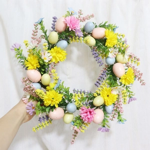 Close-up of Easter wreath featuring colorful eggs and blooming spring daisies