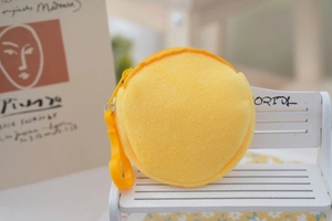 Close-up of yellow round plush pouch with plastic zipper and hook for children