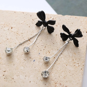 Vue macro de boucles d'oreilles papillon noir avec des pompons argentés et zircons