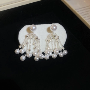 Close-up of pearl tassel drop earrings with silver metal chains on a display card