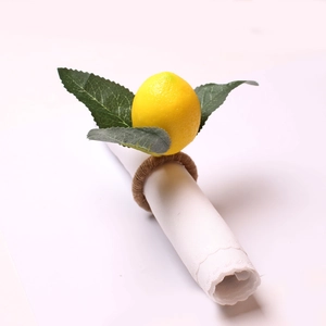 Detail of yellow lemon and green leaf napkin ring on white cloth with jute twine loop