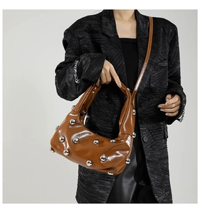 Detail of coffee brown hobo bag with large silver spherical rivets and glossy leather finish