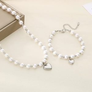 Elegant stainless steel heart charm jewelry set with pearl beads on beige fabric