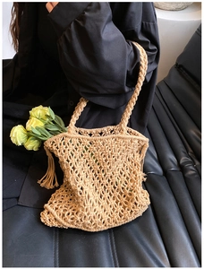 Detail of handmade hollow macramé knit shoulder bag with woven handle and fringe tassels