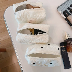 Détail montrant les finitions en dentelle et le matelassage des trousses blanches