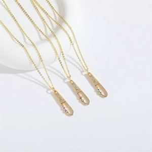 Gold safety pin necklace with zircon and colorful evil eye charms on white studio background