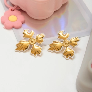 Detailed macro view of 18K gold floral stud earrings with white enamel finish