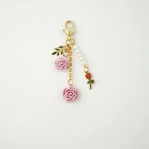 Detail of handmade resin rose keychain with pearls and heart-shaped golden lobster clasp