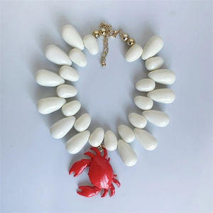 Nautical necklace with white teardrop beads and a red crab pendant on a gold chain