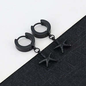 Close-up of black starfish charm earrings with textured matte finish on dark background