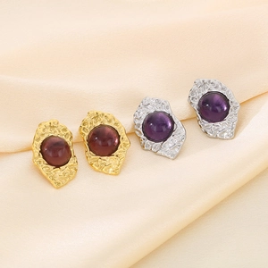 Detail of vintage 18K gold and silver earrings with cat eye stones on silk background