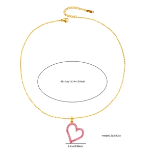 Detail of a golden heart pendant with pink crystals and S.STEEL stamp on the chain
