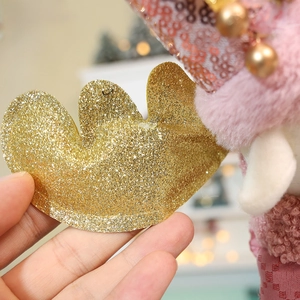 Close-up of golden glitter reindeer antlers with bell on pink plush Christmas doll