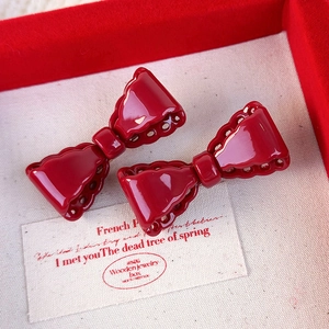 Detail of red bow hair clips with hollow wave edges in a velvet gift box