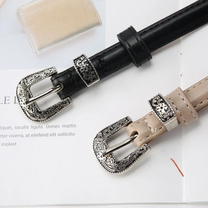 Detailed shot of retro metal engraved buckles on black and beige leather belts for women